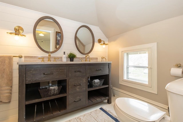 bathroom with double vanity, toilet, a sink, and lofted ceiling