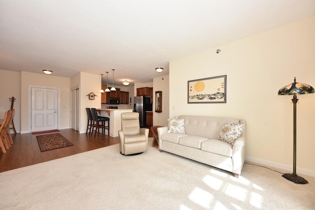living room featuring baseboards, wood finished floors, and carpet