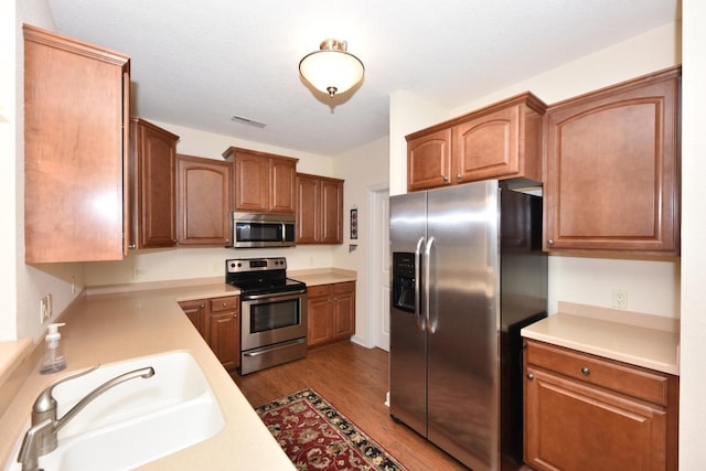 kitchen with dark wood-style flooring, visible vents, a sink, light countertops, and stainless steel appliances