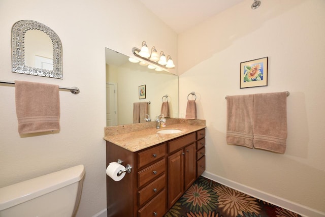 bathroom with baseboards, vanity, and toilet