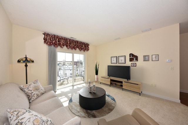 living area featuring baseboards, visible vents, and light carpet