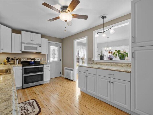 kitchen featuring range with two ovens, white cabinetry, radiator heating unit, and white microwave