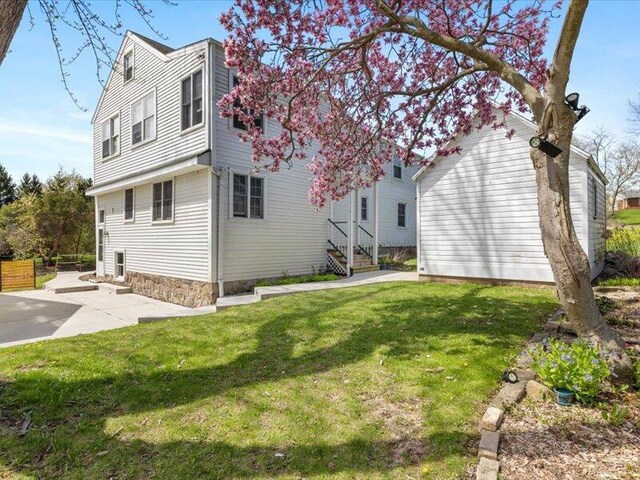 rear view of house featuring a lawn and a patio