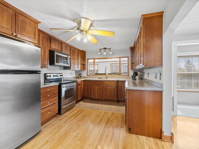 kitchen featuring light wood finished floors, brown cabinets, a wealth of natural light, and stainless steel appliances