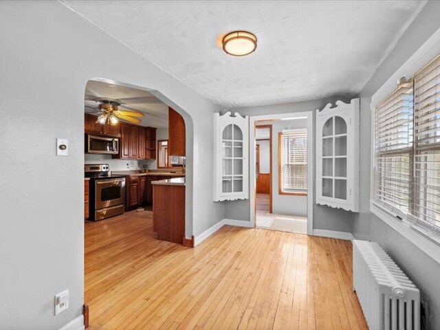 interior space with radiator heating unit, appliances with stainless steel finishes, baseboards, and arched walkways