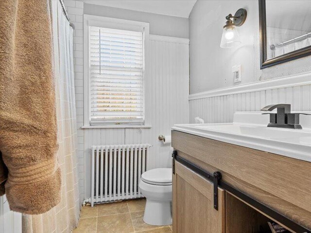 bathroom featuring radiator, vanity, toilet, and a wealth of natural light