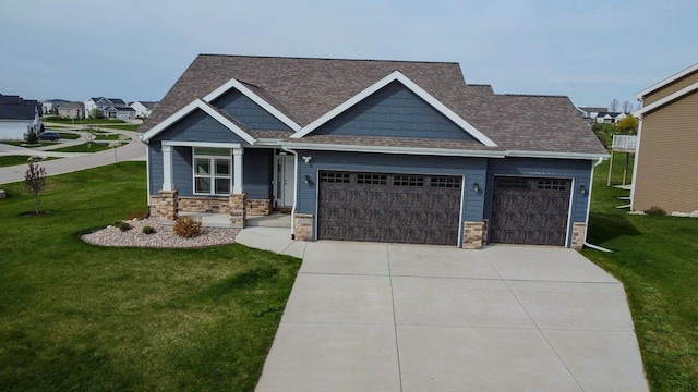 craftsman-style house featuring roof with shingles, an attached garage, stone siding, a front yard, and driveway