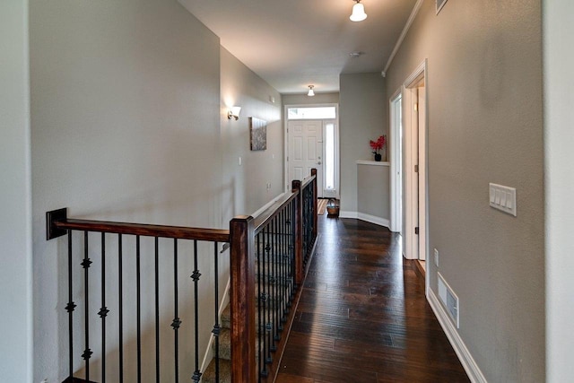 hall featuring baseboards, visible vents, ornamental molding, and dark wood-type flooring