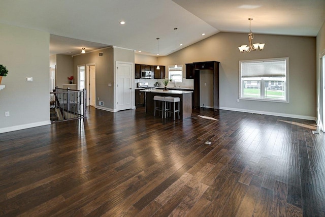 unfurnished living room featuring a wealth of natural light, a notable chandelier, vaulted ceiling, and dark wood-style floors