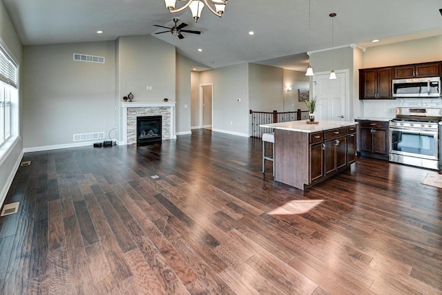 kitchen with stainless steel appliances, open floor plan, visible vents, and a kitchen breakfast bar