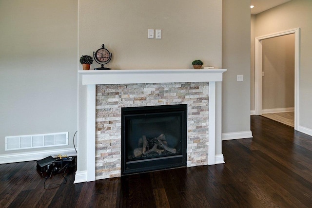interior details with baseboards, visible vents, a stone fireplace, and wood finished floors
