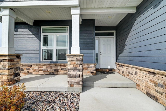 view of exterior entry with covered porch and stone siding