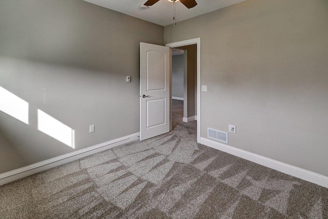 empty room with visible vents, carpet flooring, baseboards, and a ceiling fan