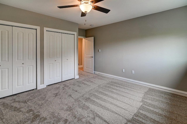 unfurnished bedroom featuring multiple closets, baseboards, carpet, and a ceiling fan