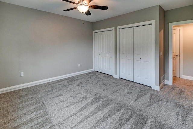 unfurnished bedroom featuring baseboards, carpet, multiple closets, and ceiling fan