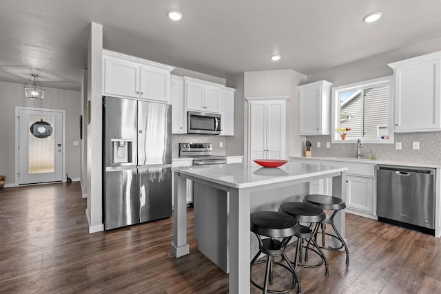 kitchen with a center island, white cabinetry, appliances with stainless steel finishes, and a kitchen bar