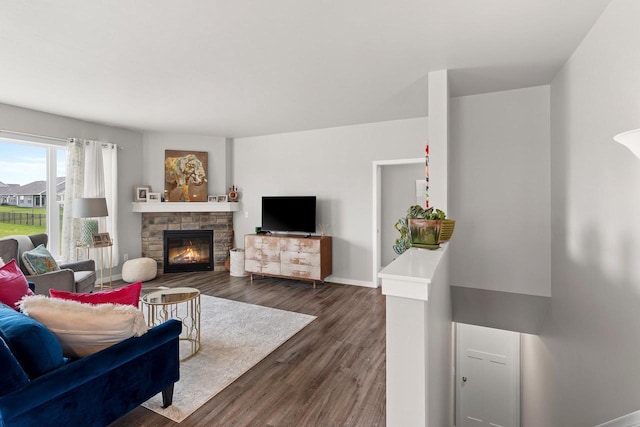 living area featuring baseboards, dark wood-style flooring, and a fireplace