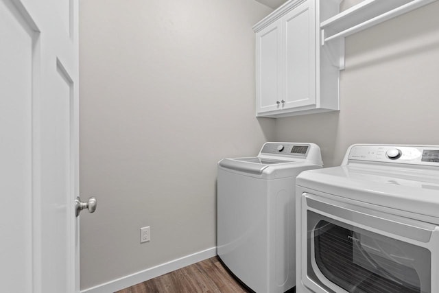washroom with baseboards, dark wood-style floors, cabinet space, and washer and clothes dryer