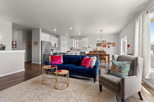 living area with an inviting chandelier, recessed lighting, baseboards, and wood finished floors