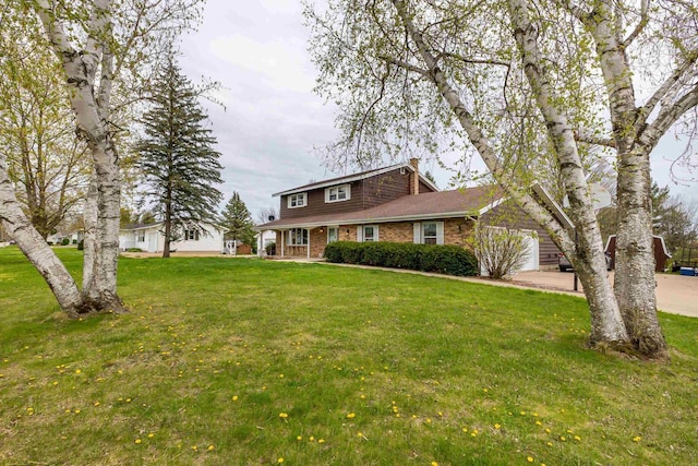 view of front of property featuring brick siding, driveway, and a front yard