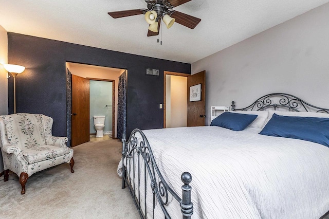 bedroom with light colored carpet, a ceiling fan, and ensuite bath