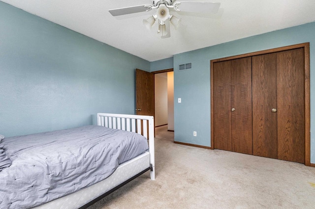 carpeted bedroom with a ceiling fan, baseboards, visible vents, and a closet