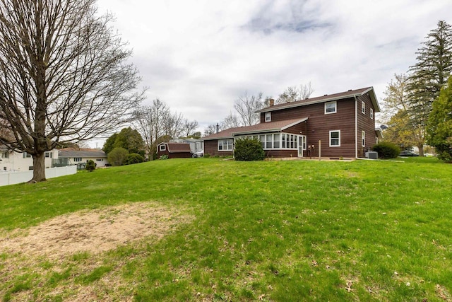 view of yard featuring central air condition unit, fence, and a sunroom