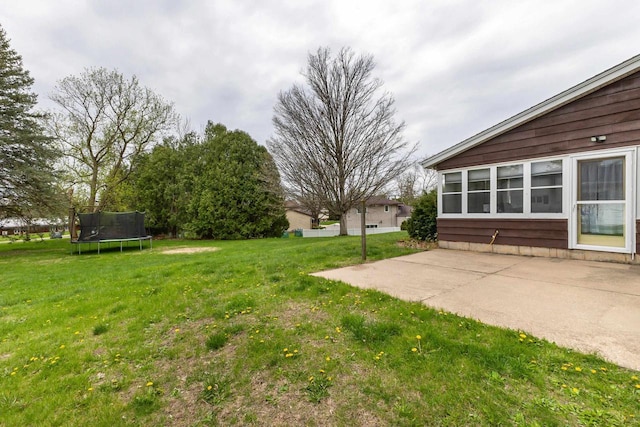 view of yard with a trampoline and a patio area
