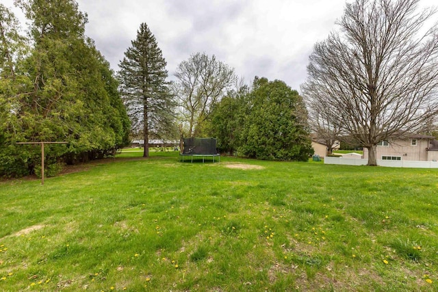 view of yard featuring a trampoline and fence
