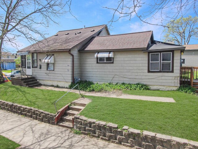 back of property with a shingled roof and a yard