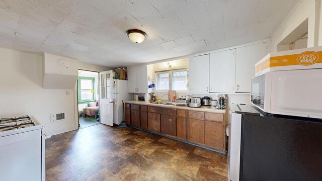 kitchen with light countertops, a sink, a healthy amount of sunlight, and white appliances