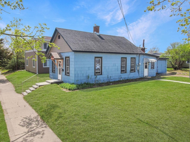 view of front of home featuring roof with shingles, a chimney, and a front lawn