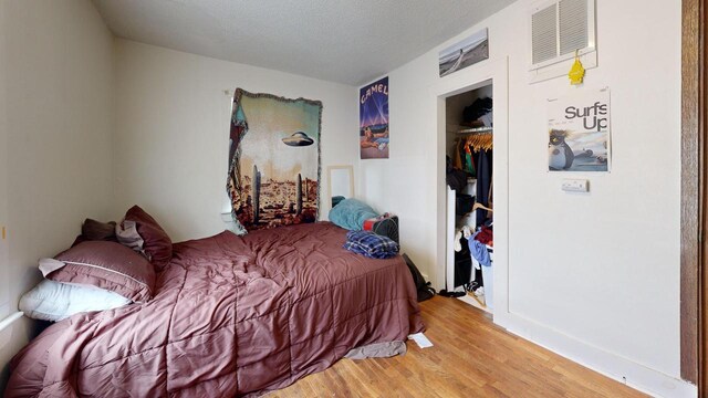 bedroom featuring visible vents, a textured ceiling, wood finished floors, and a closet