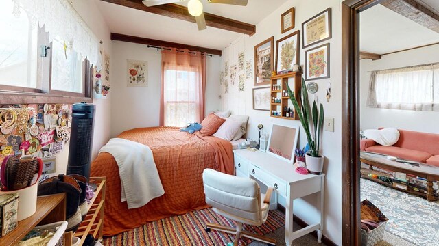 carpeted bedroom with a ceiling fan and beamed ceiling