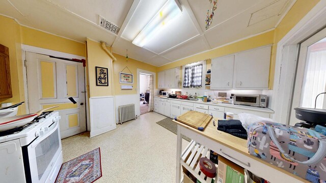 kitchen featuring radiator heating unit, white cabinetry, stainless steel microwave, visible vents, and white range with gas cooktop