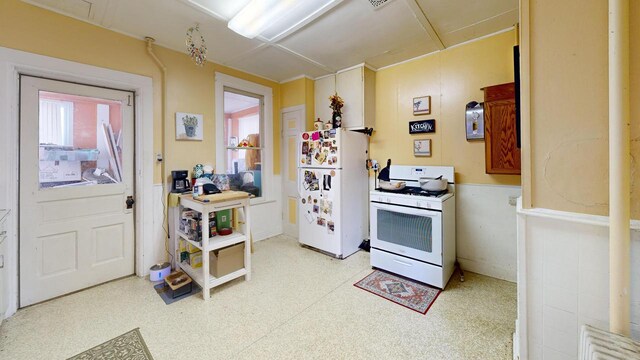 kitchen featuring light floors, wainscoting, and white appliances