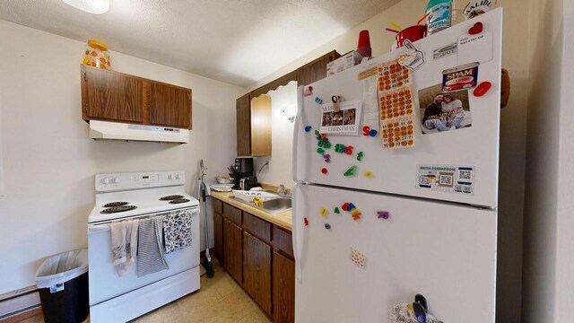 kitchen with white appliances, light countertops, a baseboard heating unit, under cabinet range hood, and a sink