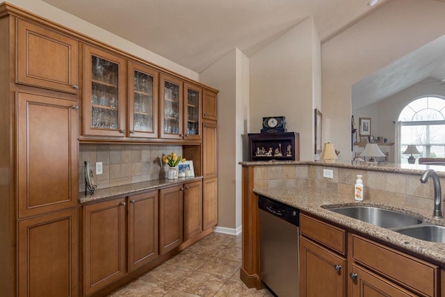 kitchen with a sink, brown cabinetry, vaulted ceiling, and dishwasher