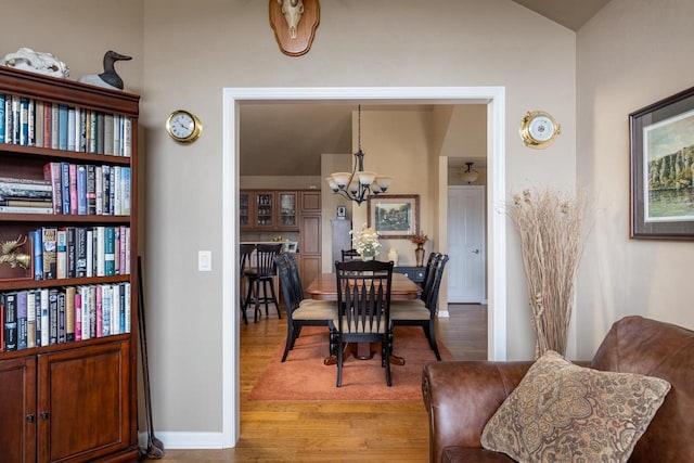 dining area featuring baseboards, an inviting chandelier, wood finished floors, and lofted ceiling