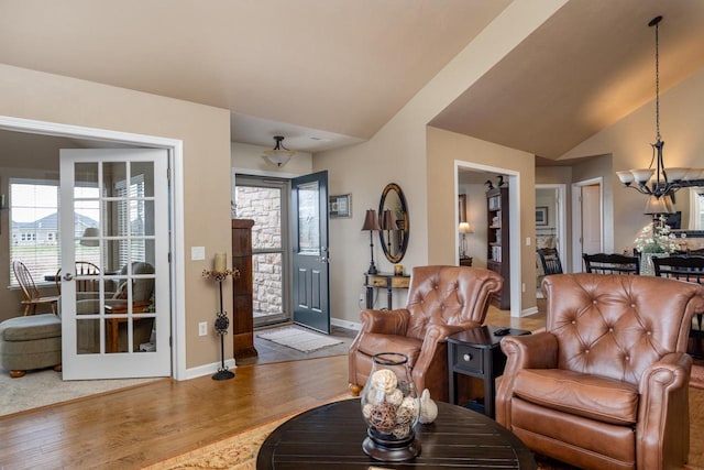 living room with a chandelier, wood finished floors, vaulted ceiling, and a healthy amount of sunlight
