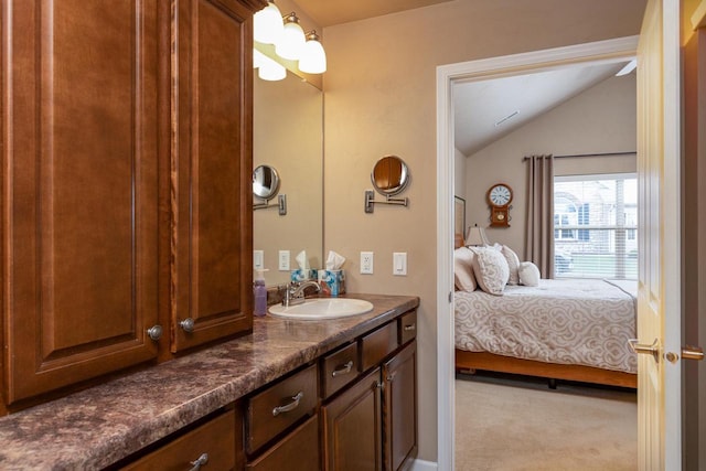 ensuite bathroom featuring connected bathroom, vaulted ceiling, and vanity