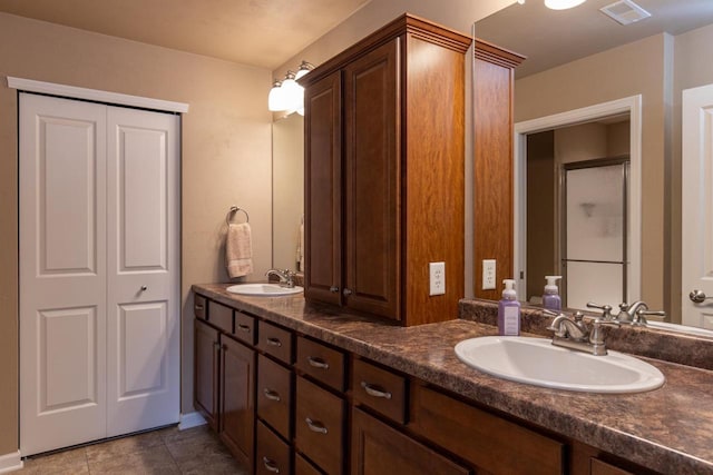 full bath featuring double vanity, visible vents, a sink, and a closet
