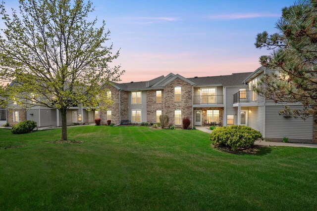 traditional home with a yard, brick siding, and a balcony