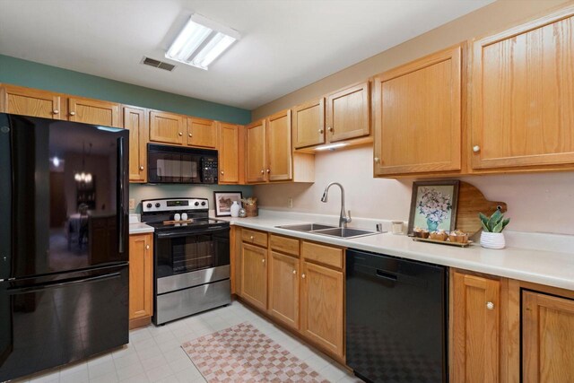 kitchen featuring a sink, light countertops, black appliances, and visible vents