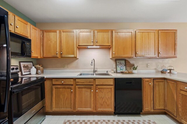 kitchen with brown cabinetry, a sink, black appliances, and light countertops