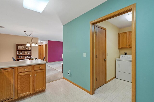 kitchen featuring light countertops, a chandelier, brown cabinetry, washer / clothes dryer, and pendant lighting