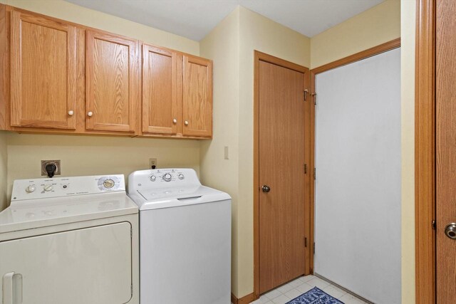 laundry area with cabinet space, light tile patterned floors, and washer and clothes dryer