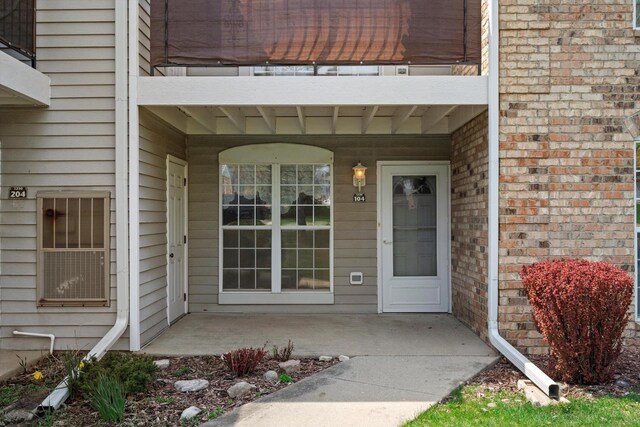 doorway to property featuring brick siding, a balcony, and a porch
