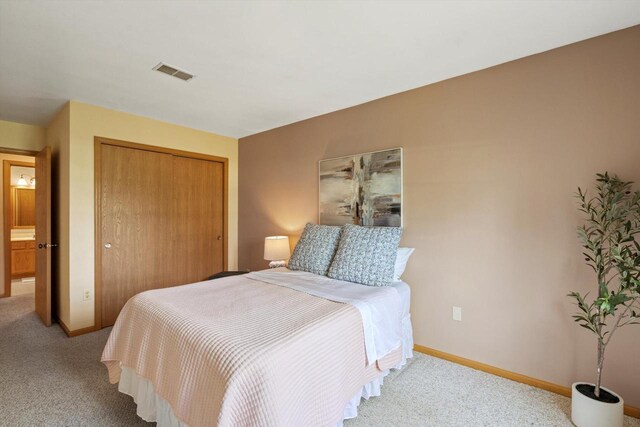 bedroom featuring baseboards, visible vents, light carpet, and a closet