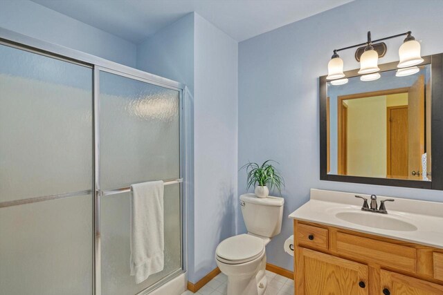 bathroom featuring vanity, toilet, baseboards, and a stall shower